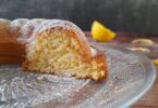 un moelleux citron amandes coupé avec des morceaux de citron en arrière plan